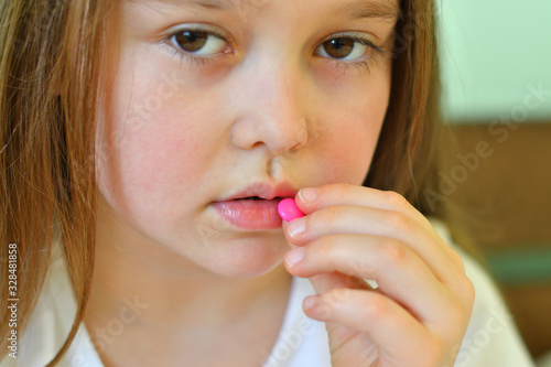 Little child girl takes pills against colds and fluSick child with napkin in bed. Allergic kid, flu season. Kid with cold rhinitis, get cold snot nose. virus and infection