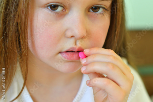 Little child girl takes pills against colds and fluSick child with napkin in bed. Allergic kid, flu season. Kid with cold rhinitis, get cold snot nose. virus and infection