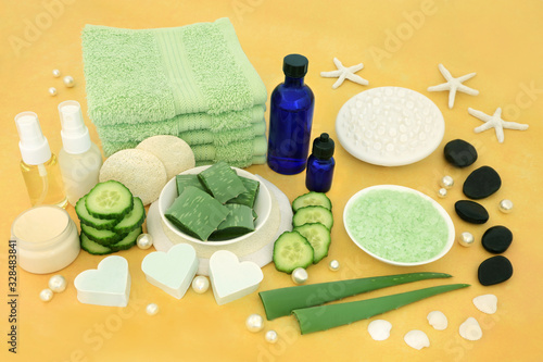 Natural spa vegan skincare beauty treatment with aloe vera & cucumber, spa stones, aromatherapy essential oils, ex foliation & cleansing products on yellow background.