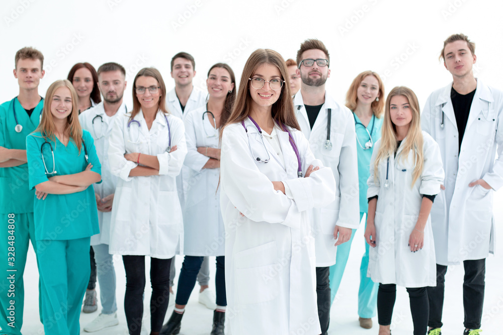 smiling young doctor standing in front of a group of medical workers smiling young doctor standing in front of a group of medical workers