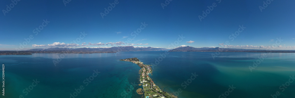 Sirmione town, Lake Garda, Italy. Aerial view of Sirmione high altitude.  In the background mountains in the snow and blue sky. Aerial panorama