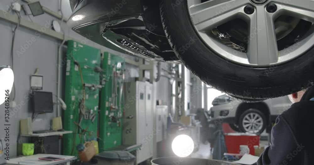 Auto Mechanic Working Under The Car In Dealer's Garage. Auto Mechanic Working Under The Car In Dealer's Garage.