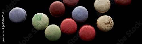top view of assorted delicious colorful french macaroons isolated on black, panoramic shot