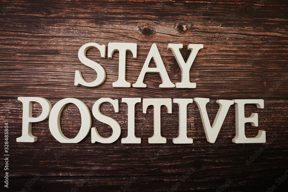 Fototapeta premium Stay Positive alphabet letter on wooden background