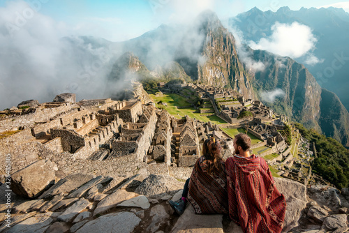 Couple dressed in ponchos watching the ruins of Machu Picchu