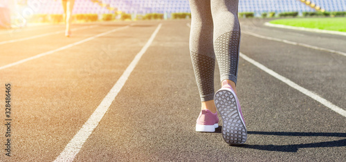Crop image of female sporty legs and feet in running shoes at the stadium