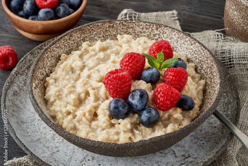 Oatmeal rustic porridge with blueberry, raspberries in ceramic vintage bowl, dash diet with berries