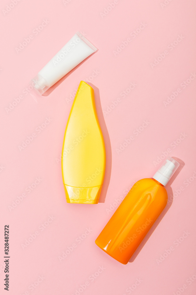 Top view of tubes and dispenser bottle of sunscreen on pink background Top view of tubes and dispenser bottle of sunscreen on pink background