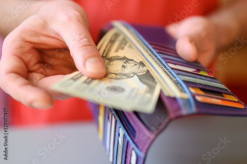 men's hands hold 20 dollar bills and a wallet on a gray table