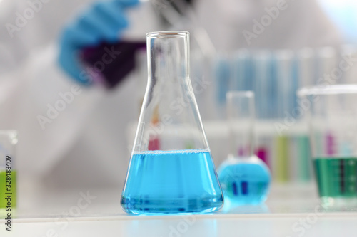 Chemical industry bulb with blue magenta pink liquid lab tubes stand on the table in the laboratory of liquid testing test development substances poisons additives stabilizers flavors house cleaning.