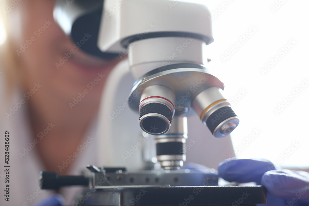 Woman look microscope on the background laboratory is a study human biology analyzes for non-compliance with the requirements organization public health at international level
