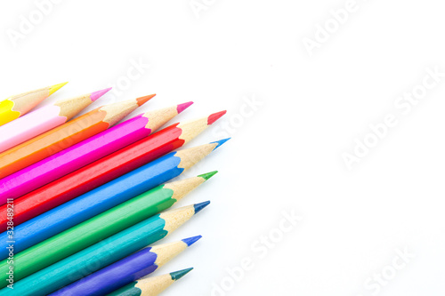 Multicolored wooden sharpened pencils neatly folded in a cone on a large isolated background in the corner. There is free space for text.