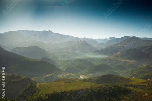Hazed landscape with forest valley and mountains background