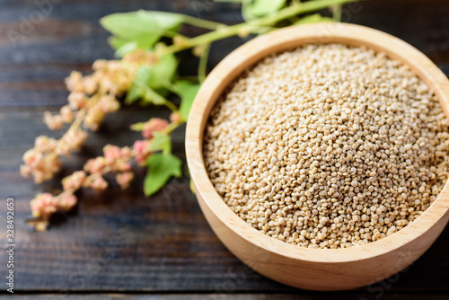 Organic raw brown quinoa seed (Chenopodium quinoa) in a bowl on wooden background, healthy food photo