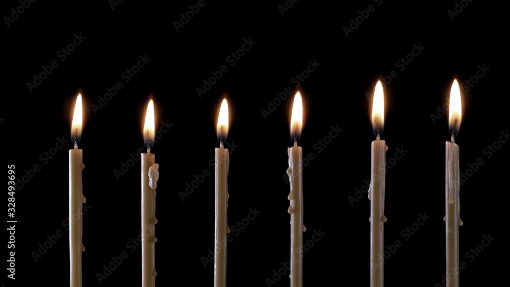 A few candles burn. Isolated candle burning with dark background. Wax candle with yellow shades burns on a black background. Background or illustration of remembrance. A few candles burn. Isolated candle burning with dark background. Wax candle with yellow shades burns on a black background. Background or illustration of remembrance.