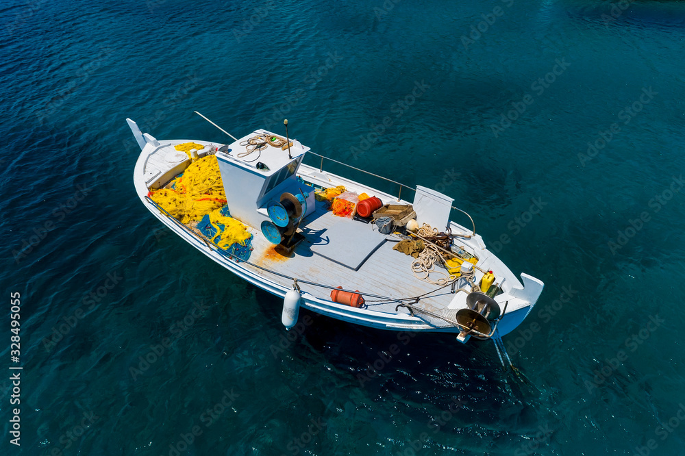Aerial photo top view of small traditional fishing boat in tropical emerald and turquoise clear sea
