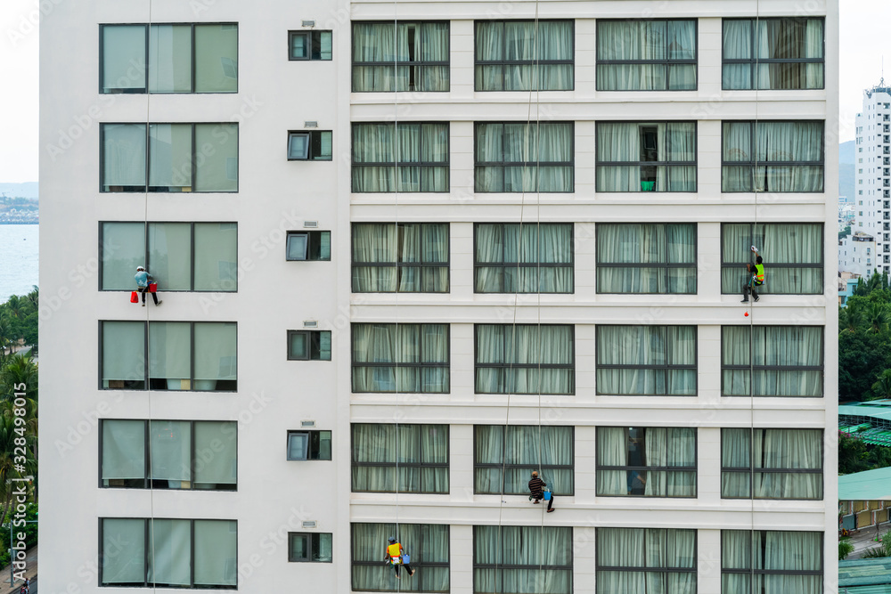 Asian industrial worker cleaning windows of a modern building.