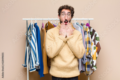 young cool berded man with clothes against flat wall photo