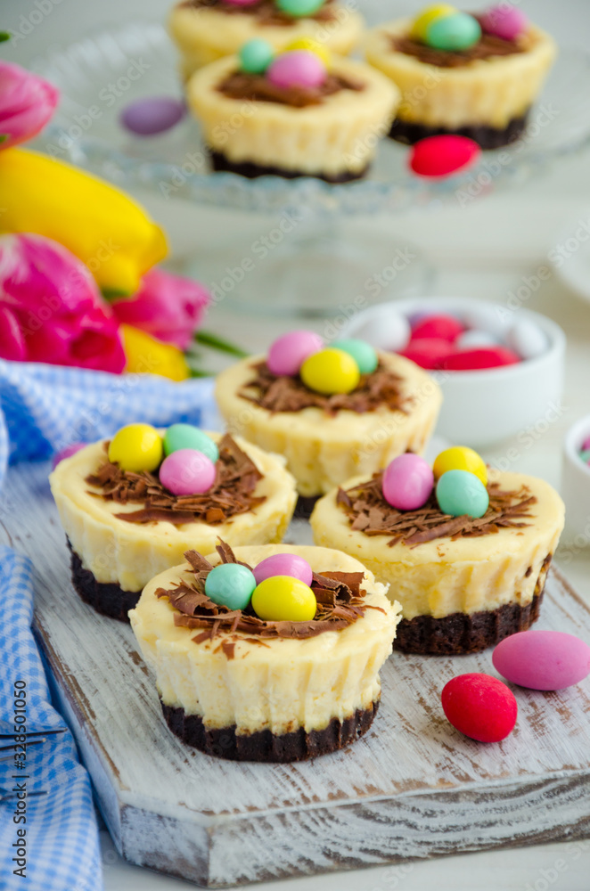 Easter mini brownie cheesecake Bird's Nest with chocolate and candy eggs. Easter dessert. Funny food idea for children. Vertical orientation. Selective focus