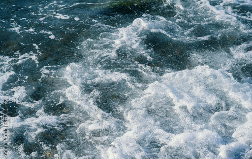 Waves at the seashore. Seafoam. Selective focus with shallow depth of field.