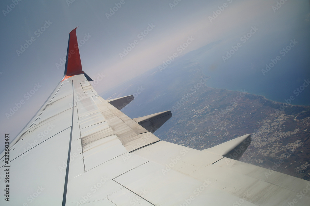 Wing of an airplane flying above the clouds. people looks at the sky from the window of the plane, using airtransport to travel.