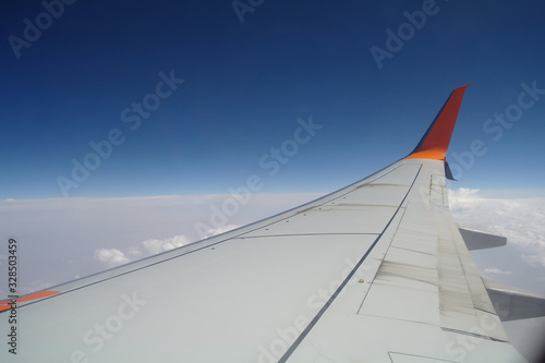 Obraz na płótnie Wing of an airplane flying above the clouds. people looks at the sky from the window of the plane, using airtransport to travel. w salonie