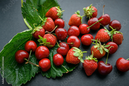 Natural looking cherry and strawberry on a dark background. Selective focus.