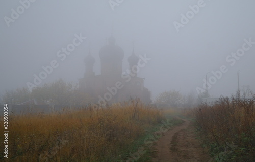 Obraz na płótnie Autumn landscape with fog and the road to the church w salonie