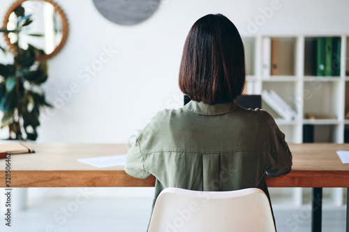 Young woman sitting at wooden desk and working in office