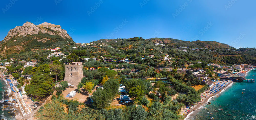 Aerial view of rocky beach, coastline of the village of Nerano. Private and wild beaches. Turquoise, blue surface of the water. Vacation and travel concept. Old tower and campsite for motorhomes