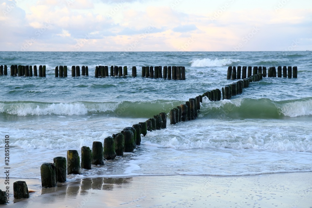 Fototapeta premium Waves crashing on the breakwater on a sunny day. Baltic Sea coast, Dziwnowek, Poland