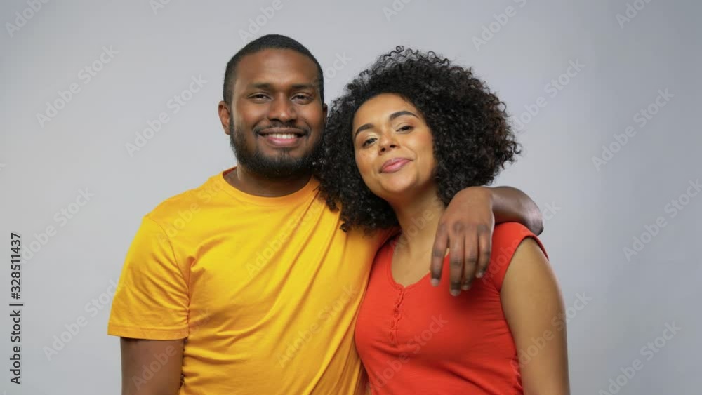love, relationships and valentines day concept - happy african american couple hugging and kissing over grey background love, relationships and valentines day concept - happy african american couple hugging and kissing over grey background