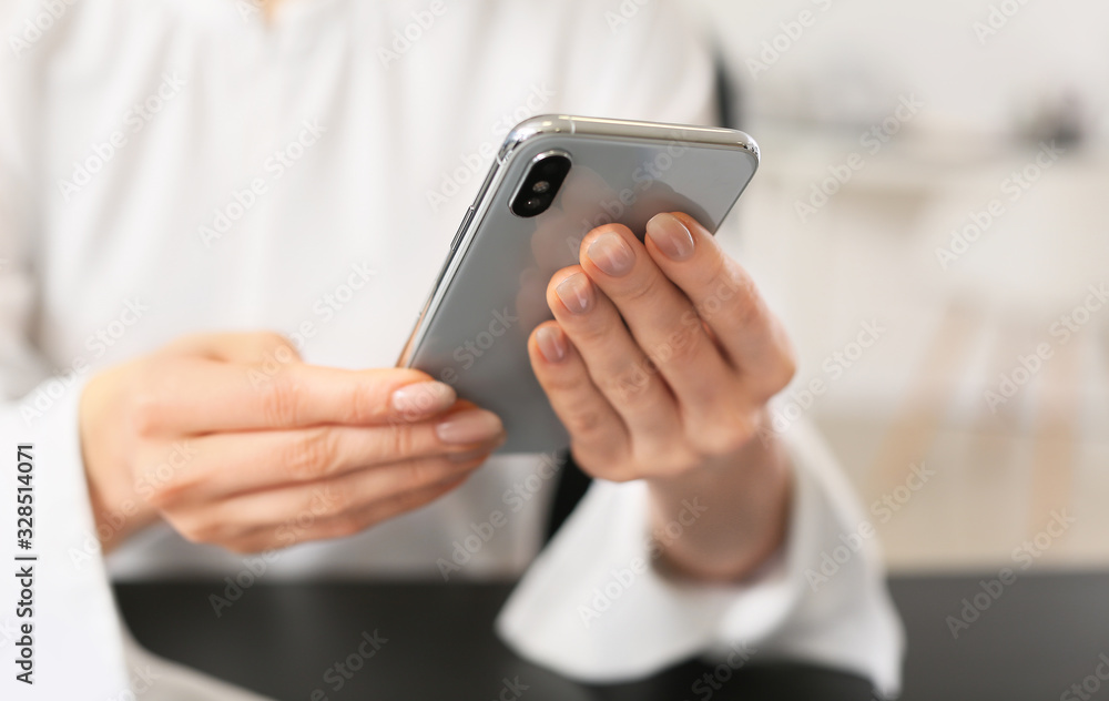 Young woman with mobile phone in office, closeup Young woman with mobile phone in office, closeup