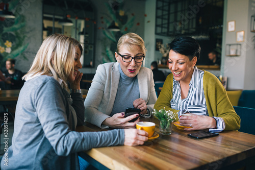 woman friends on coffee break at cafe  using smartphone