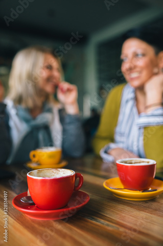 close up of coffee, woman friends talking in blurred background