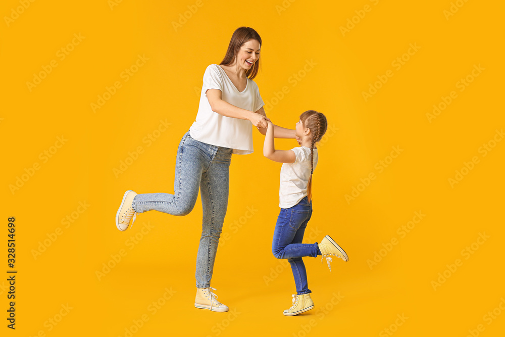 Happy mother and her little daughter dancing against color background Happy mother and her little daughter dancing against color background