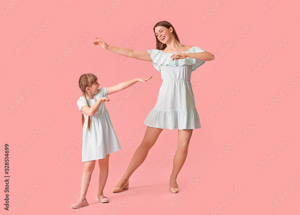 Happy mother and her little daughter dancing against color background Happy mother and her little daughter dancing against color background
