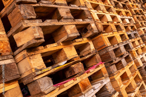 A lot stacks of used  wooden pallets of euro type on warehouse is ready for recycling. Industrial background. Close-up. © Dmytro Furman