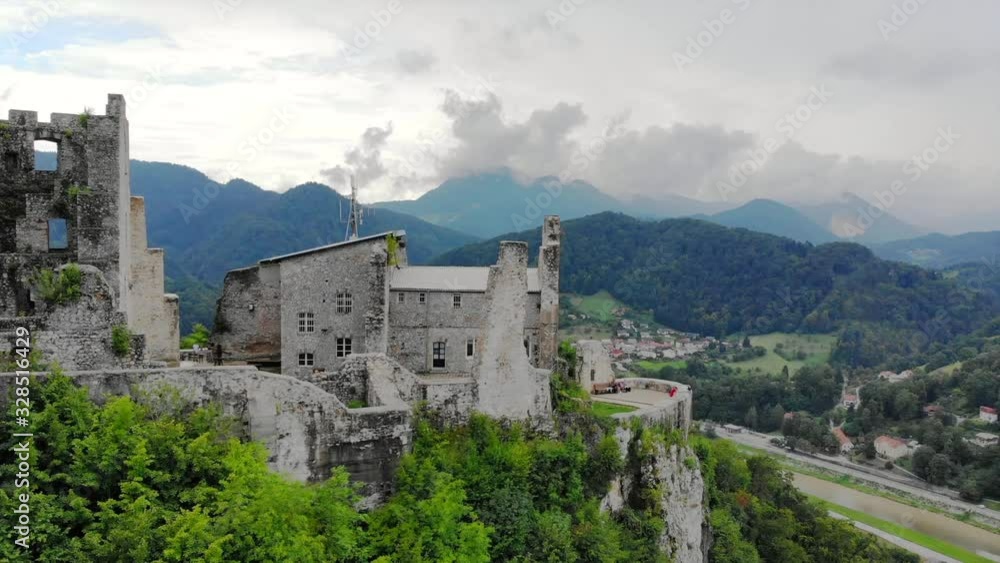 Aerial view of the ruin of Old Castle of Celje on a mountaintop surrounded by green forests. Drone zoom out. Aerial view of the ruin of Old Castle of Celje on a mountaintop surrounded by green forests. Drone zoom out.