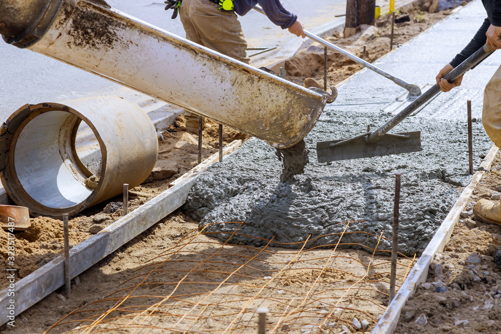 Truck loads of concrete poured into the concrete at a construction in a sidewalk Truck loads of concrete poured into the concrete at a construction in a sidewalk