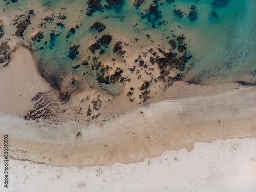 Aerial shot of beach at sunset with rocky bottom an crystal clear blue water
