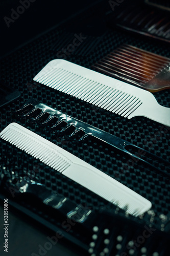 white and brown combs in a barber shop on a black table. Hair styling. Professional barber tools. © Дмитрий Ткачев