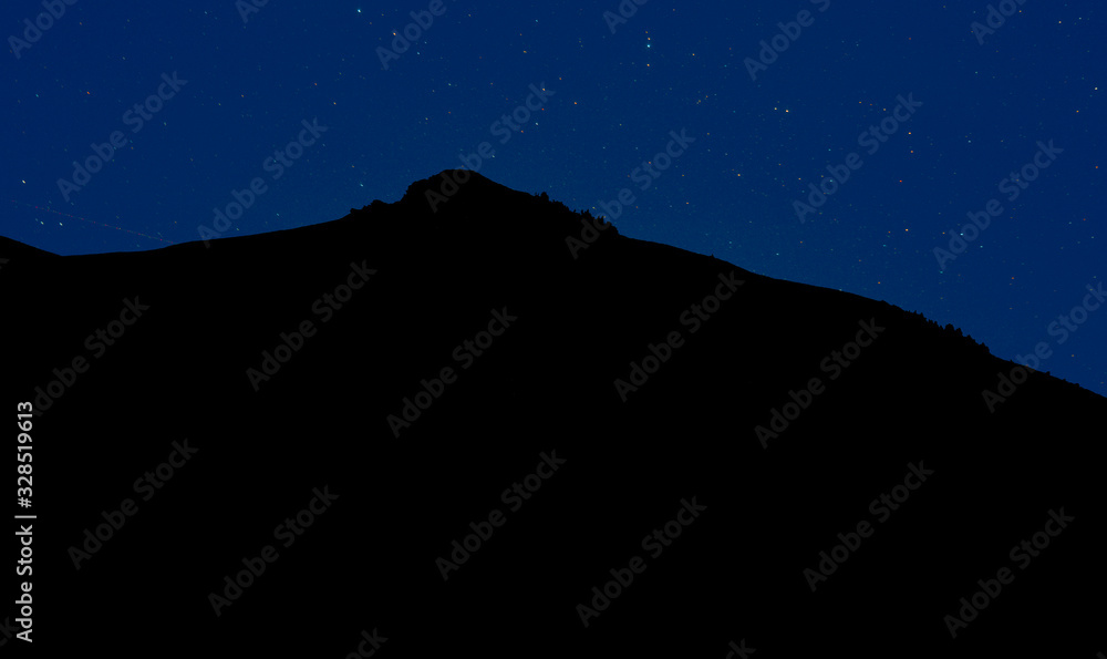 black mountain silhouette in phantom blue night sky many stars long exposure dark highland abstract background landscape
