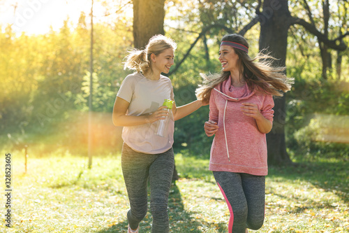 Two female friends jogging at the city park