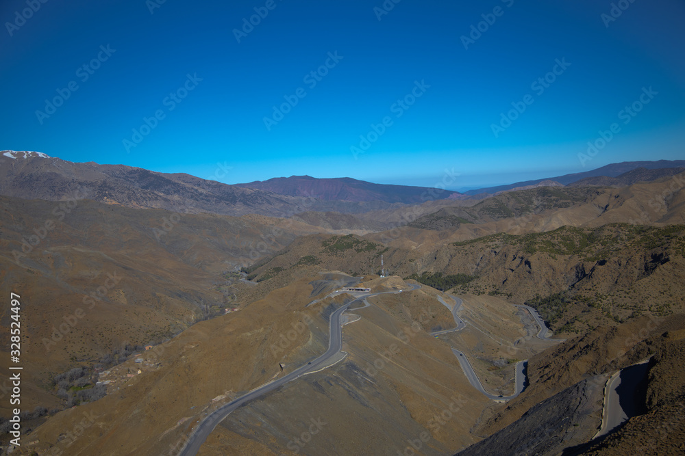Curvy road goes among the hills and mountains with clear blue sky background