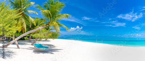 Panorama tropikalnej plaży jako letni krajobraz z huśtawką lub hamakiem i białym piaskiem i spokojnym morzem na baner plażowy. Idealna koncepcja na wakacje i wakacje na plaży. Popraw proces koloru