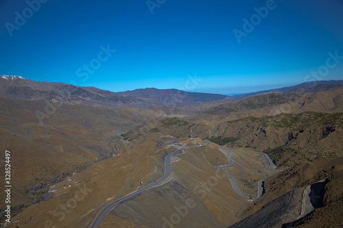 Curvy road goes among the hills and mountains with clear blue sky background