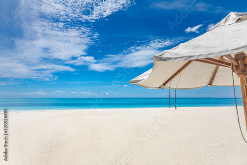 White umbrella on the beach. Parasol as summer vacation or holiday detail. Relaxation beach and tropical landscape concept. Sun umbrella under blue sky