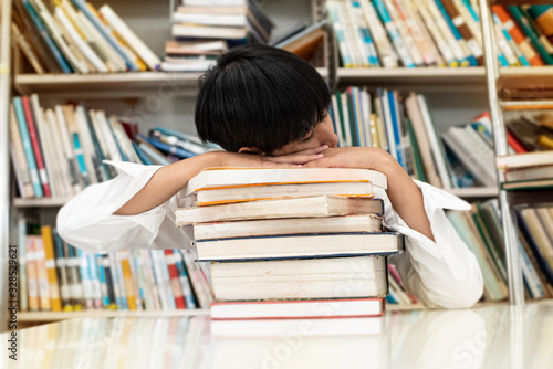 Young teenager sleeping while searching data at library,blurry light around