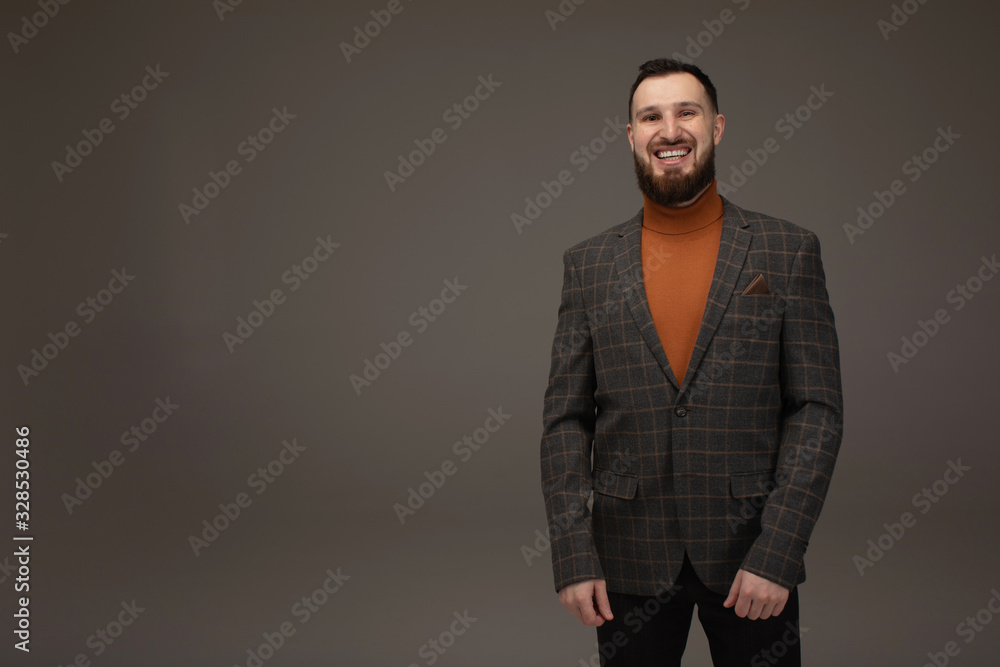 Young brunette businessman, with beard, wearing in suit on gray background Young brunette businessman, with beard, wearing in suit on gray background